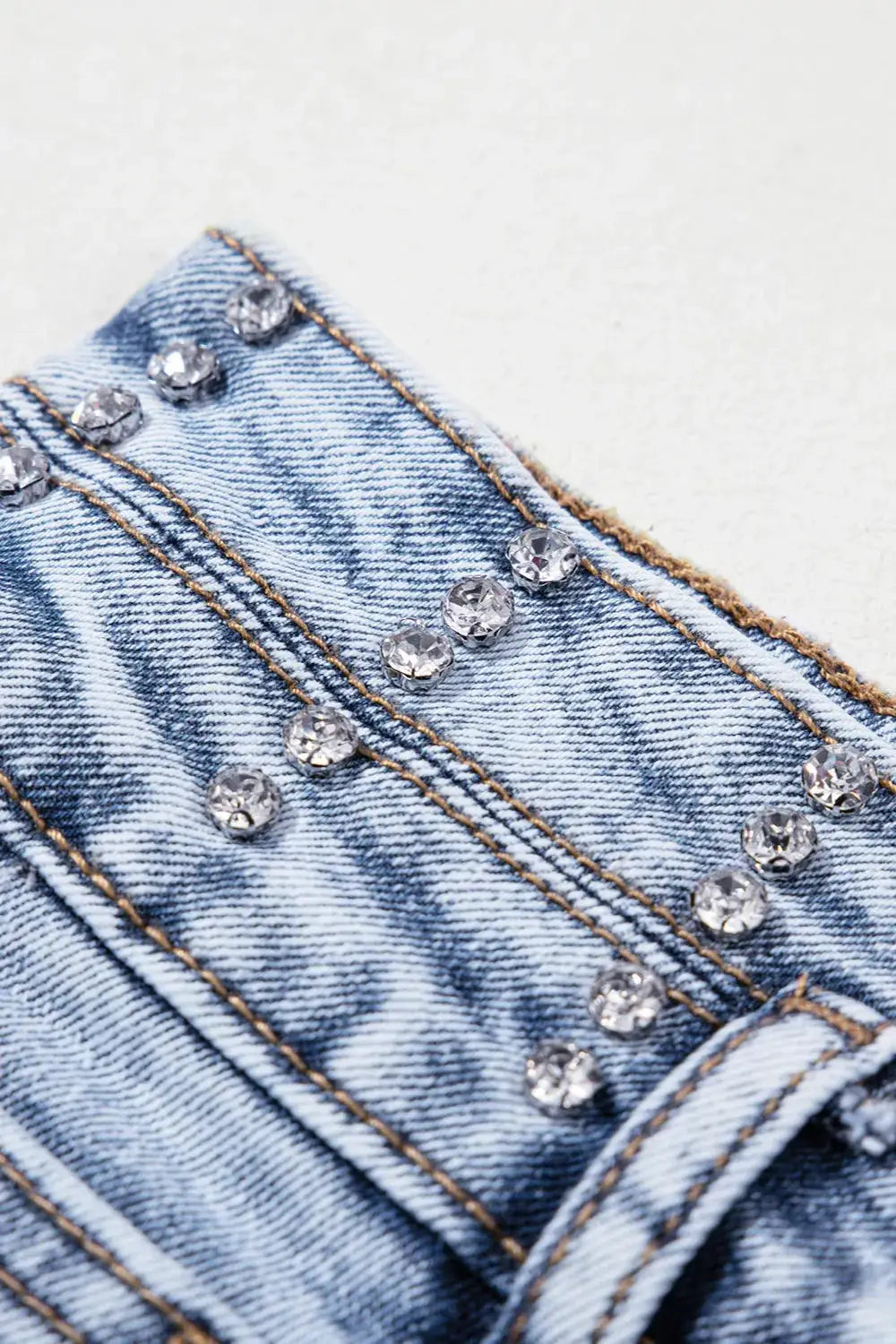 Women's high-waist light-wash denim shorts with rhinestone embellishments and a raw hem