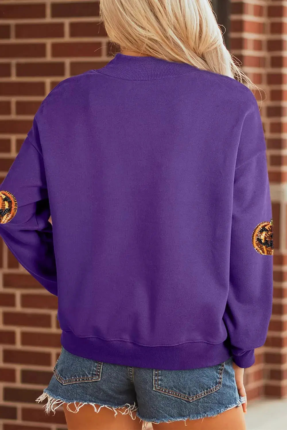 Sequin Pumpkin Spooky Halloween Sweatshirt in purple with orange sequin pumpkin patches on the sleeves