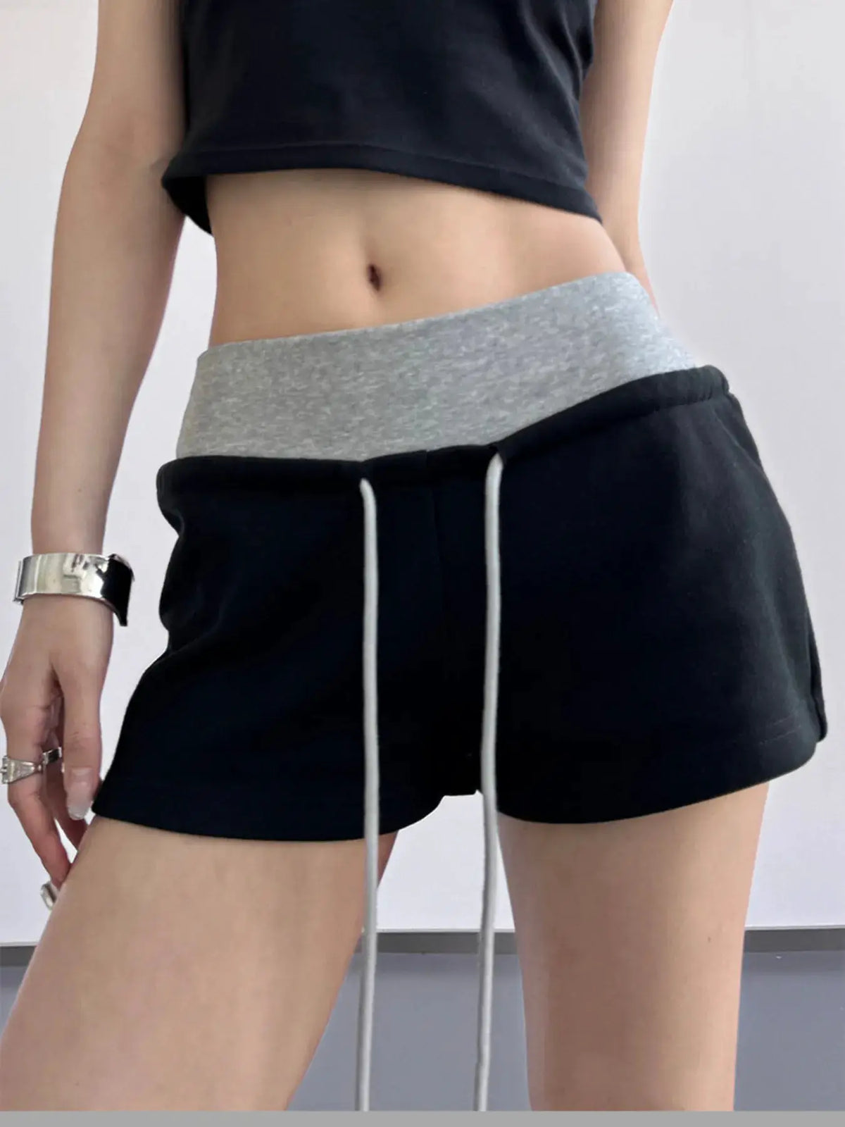 Drawstring shorts with a grey waistband on black fabric and white drawstrings.