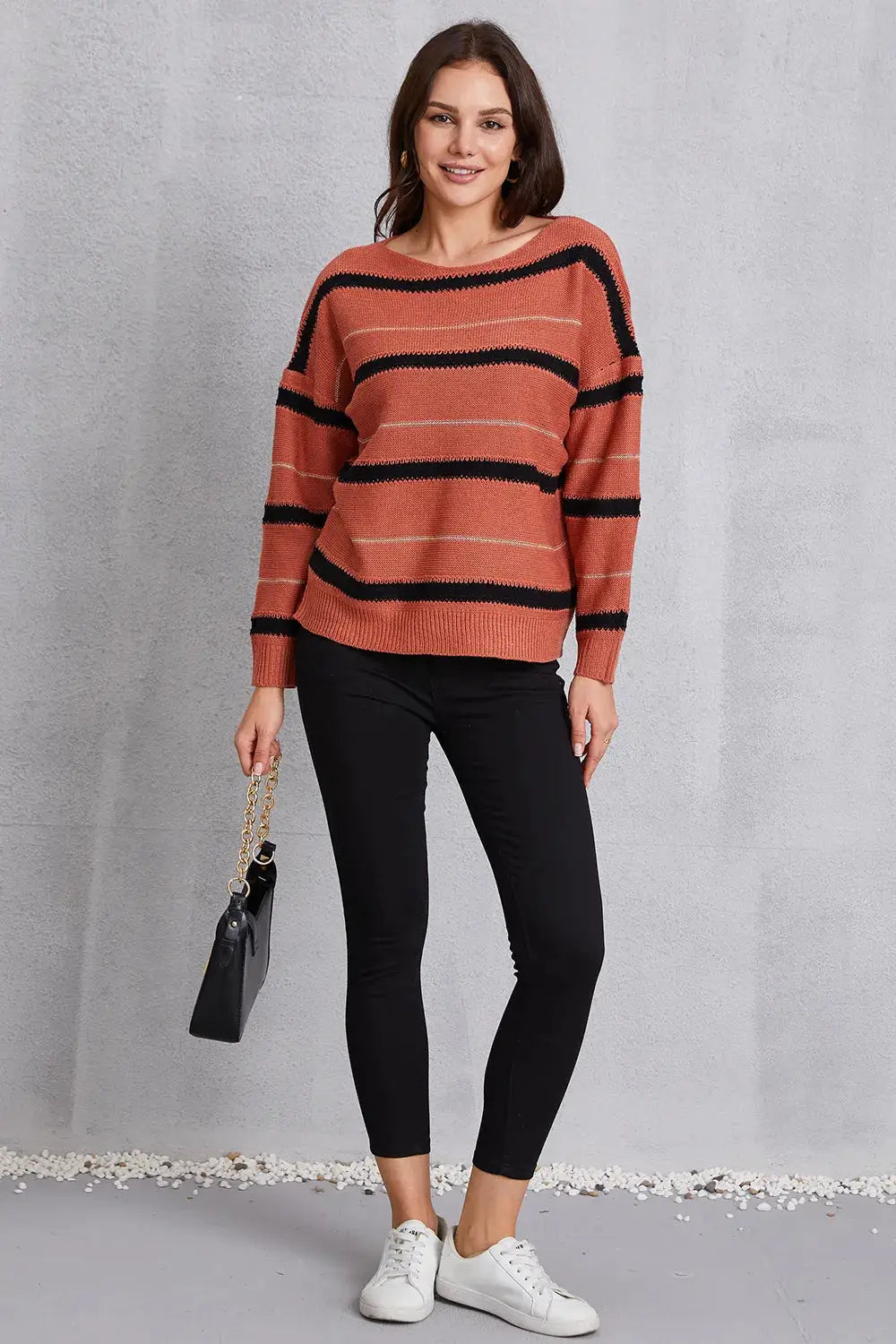 Relaxed round-neck striped knit sweater with dropped shoulders in rust and black.