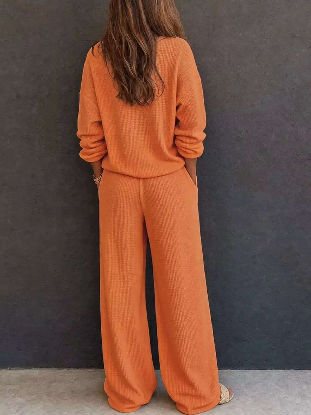 Waffle Knit Henley Top and Wide-Leg Pants Set in orange by Trendsi; back view of model in matching knit loungewear