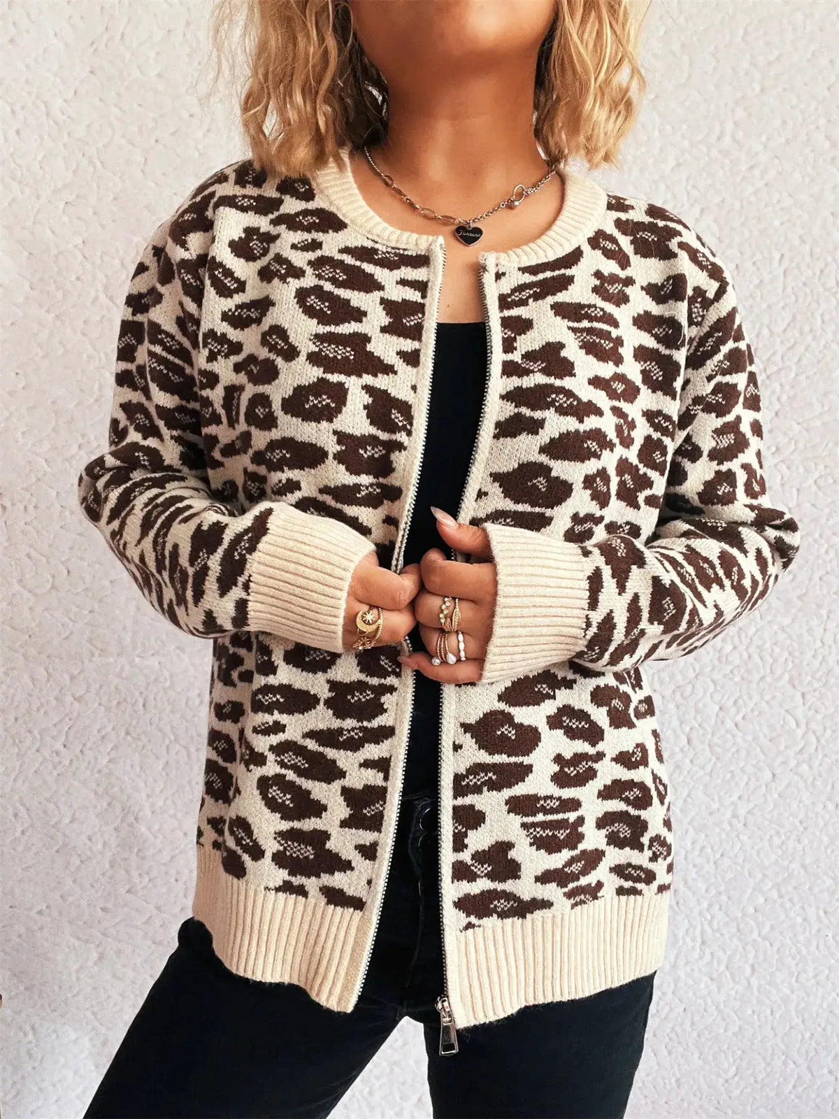 Leopard-print zip-up cardigan in beige and brown with ribbed cuffs and hem, worn over a black top.