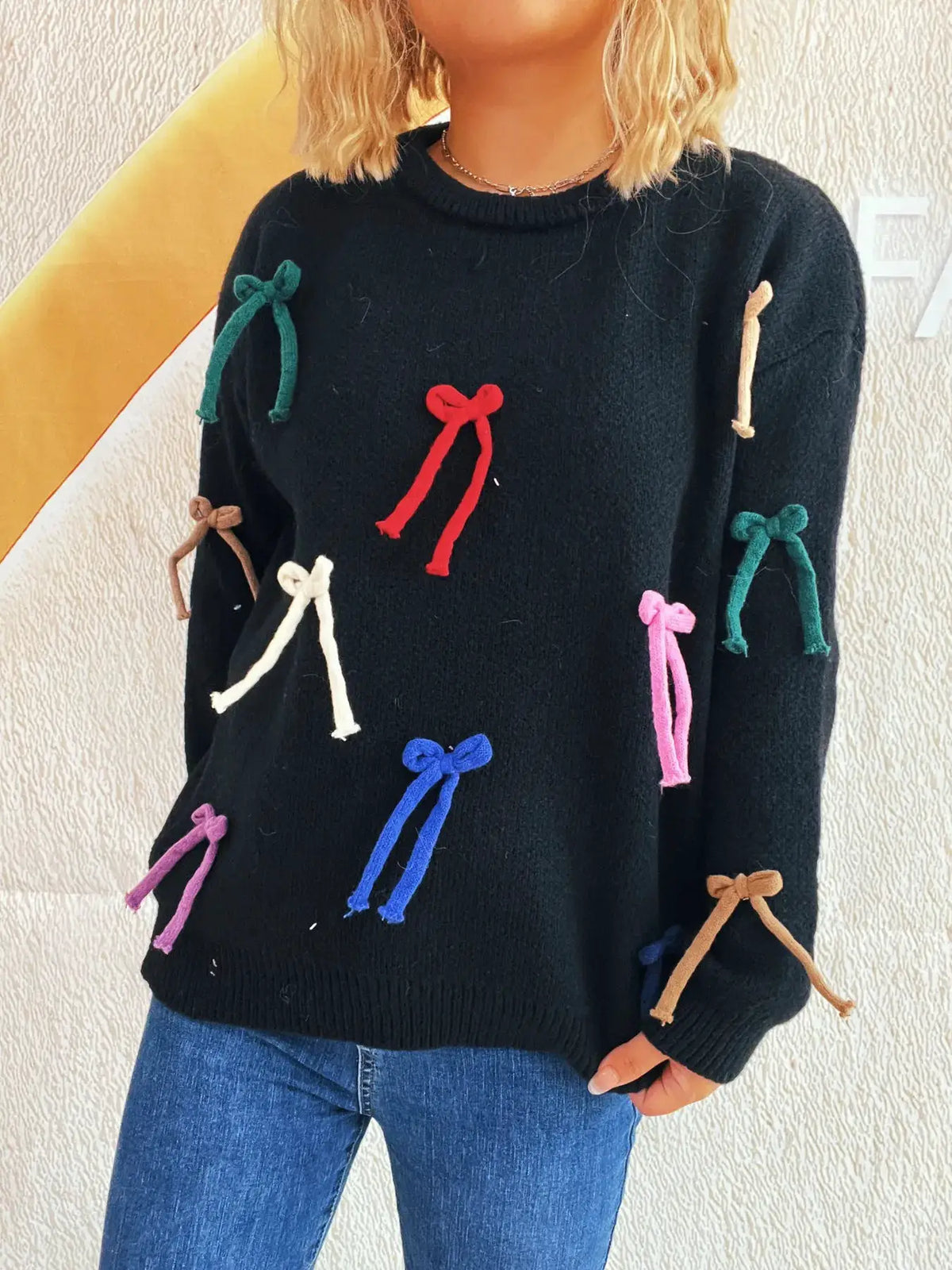 Black knit round-neck pullover for women with multicolor bow accents scattered across front and sleeves