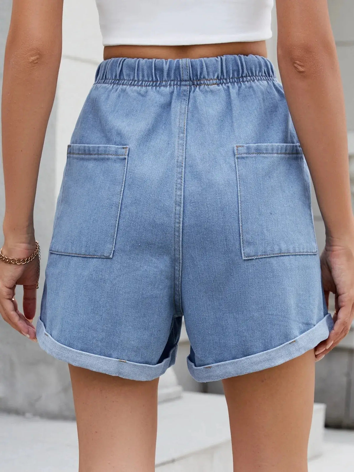 Denim shorts back view in light wash with elastic waistband, rolled cuffs, and two back pockets.