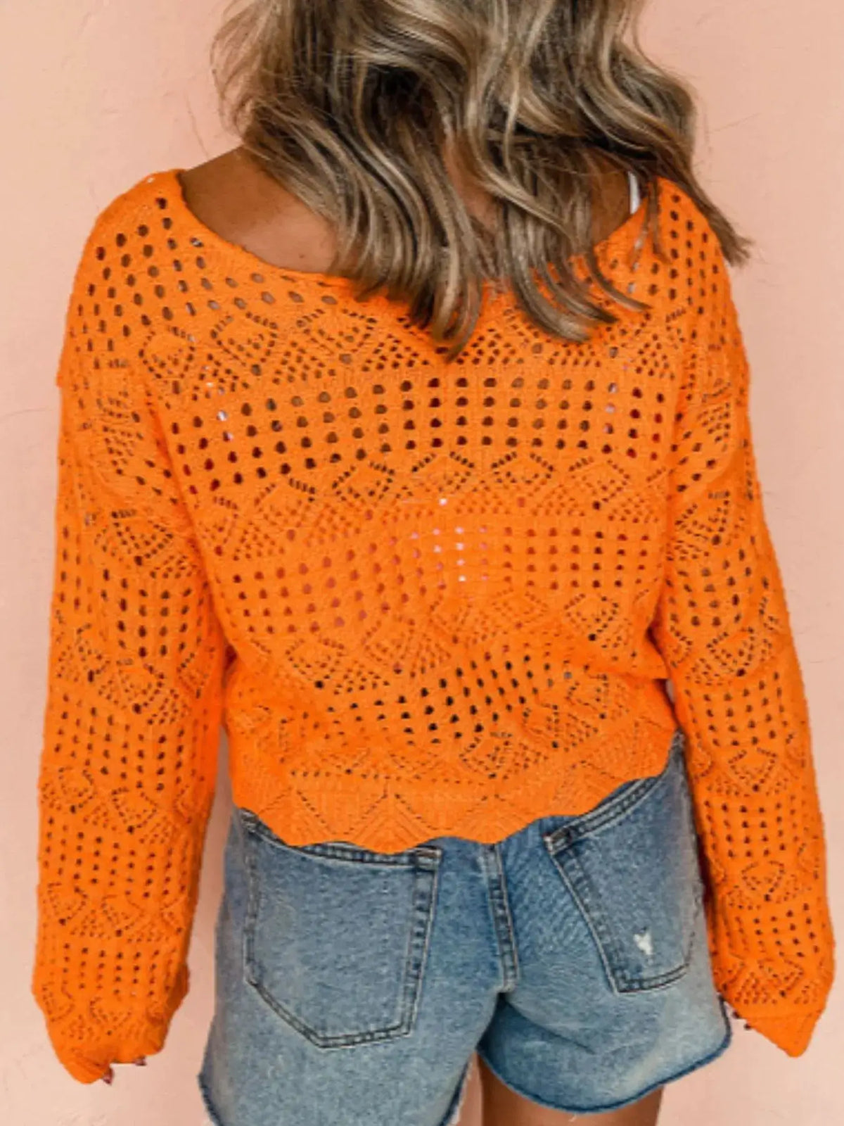 Openwork crochet boat-neck knit cover-up in bright orange, long-sleeve lightweight beachwear over denim shorts.