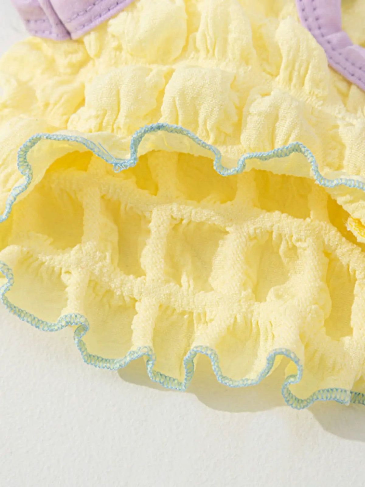 Bubble-textured yellow pet top with blue trim and ruffle detailing