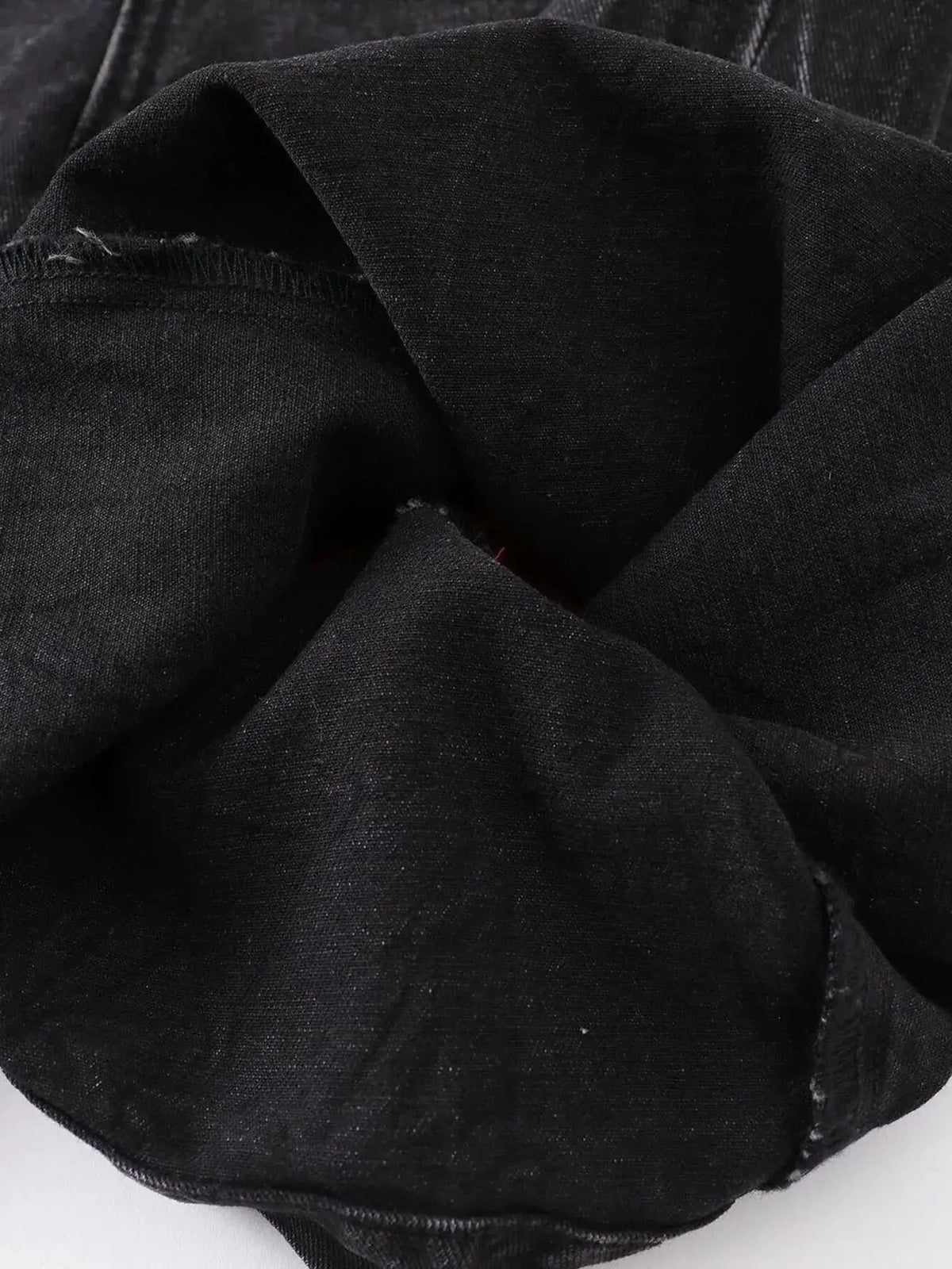 Black denim fabric close-up with textured weave and visible stitching