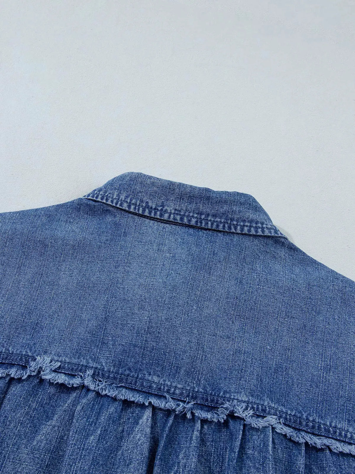 Relaxed denim shirt close-up in blue with back yoke and frayed hem