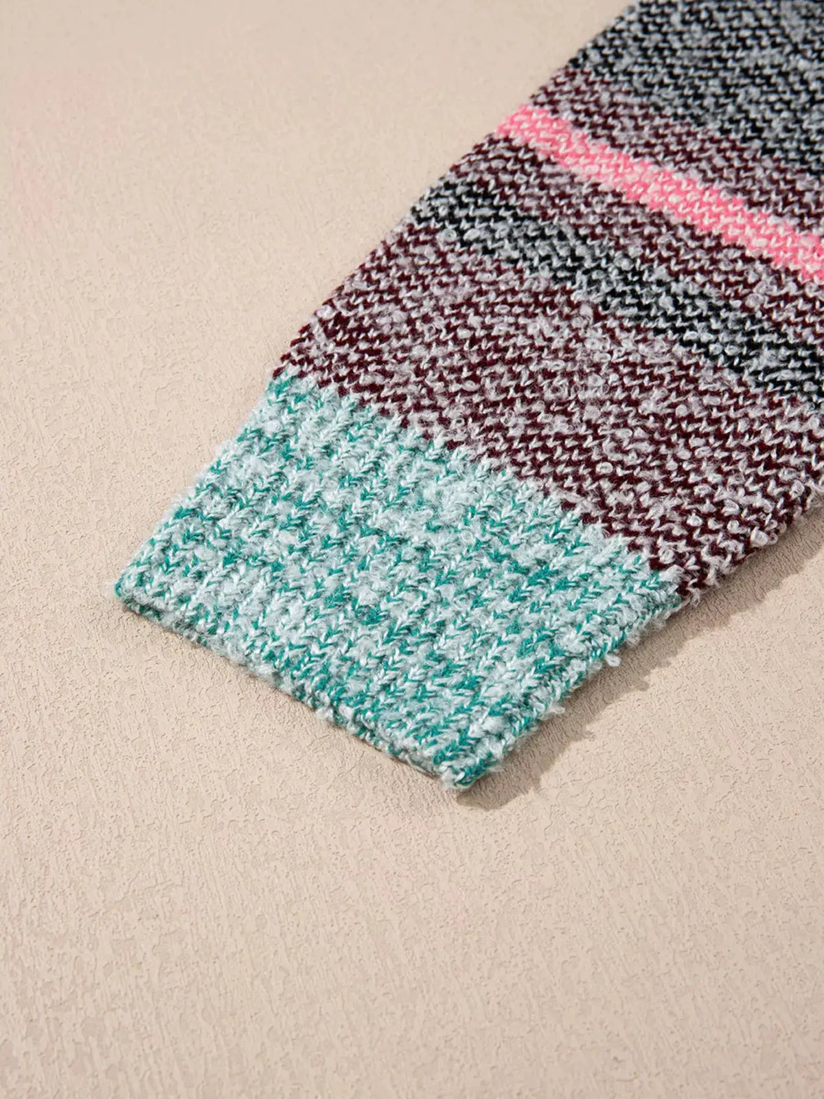Multi-color striped cardigan close-up of knit sleeve in teal, pink and maroon tones
