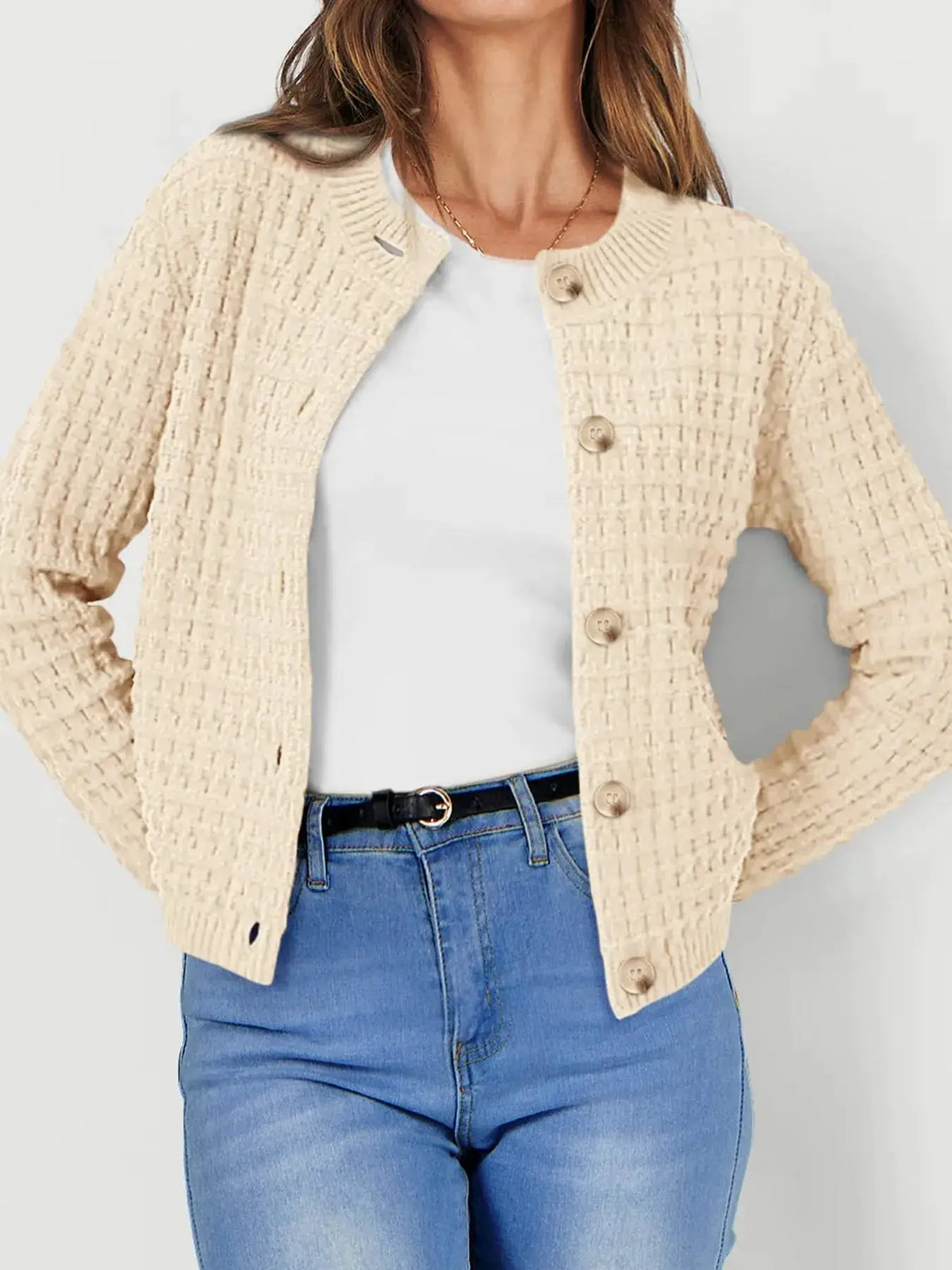Textured stretchy knit button-front cardigan in beige; versatile outerwear worn over white top with blue jeans.