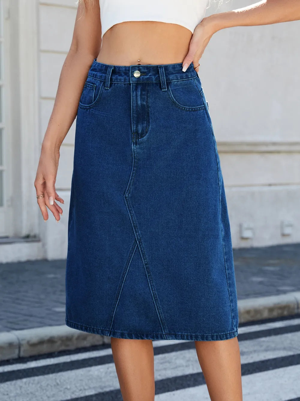 Slit-back midi denim skirt in dark blue, high-waisted with front pockets and metal button closure.