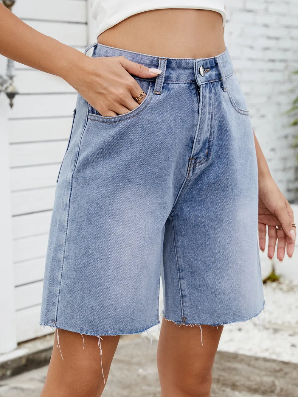 Washed light-blue denim shorts with raw frayed hems and front pockets.