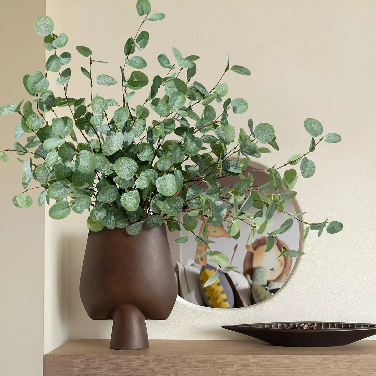 Artificial eucalyptus stems in a brown vase with green leaves for home decor