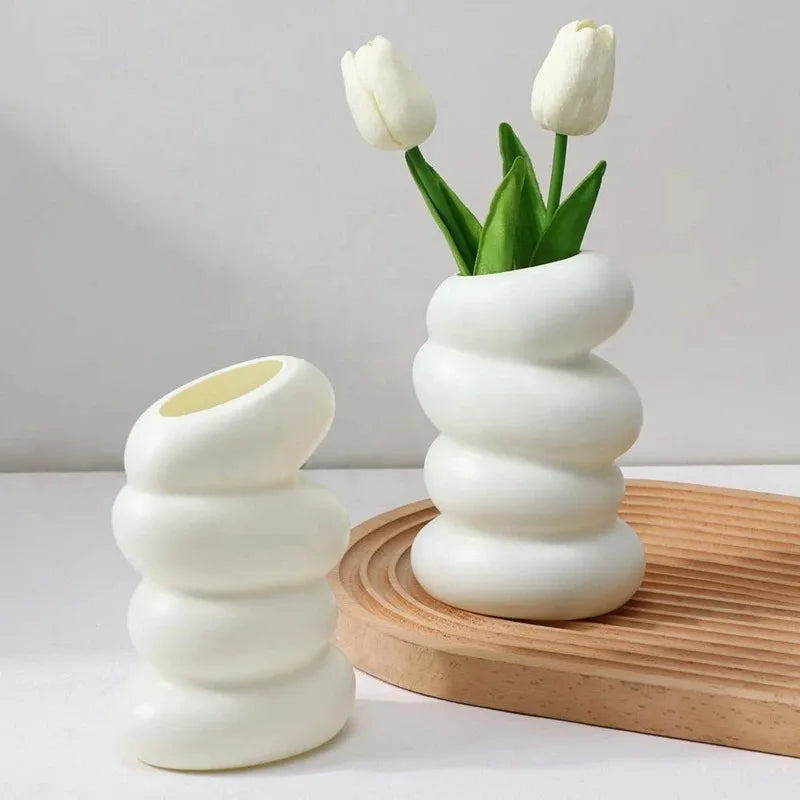 Plastic spiral white vase set; two vases, tall one with white tulips and a smaller empty piece on a wooden tray.