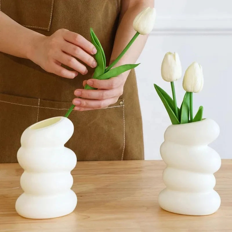 Two white plastic spiral vases on a wooden table with white tulips, Nordic creative flower arrangement accessories