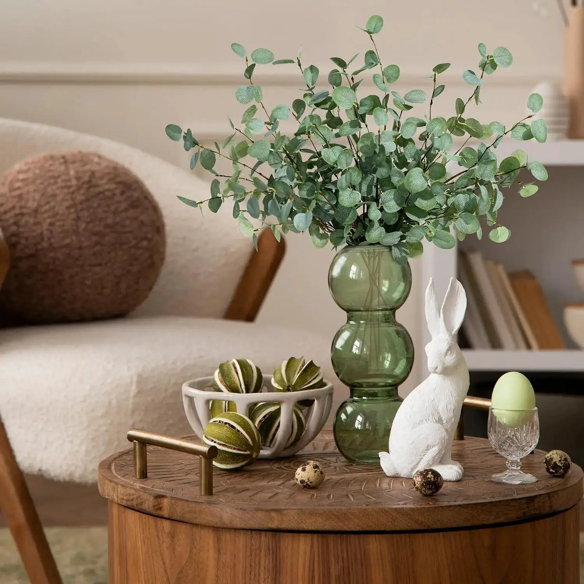 Artificial eucalyptus stems with green leaves in a green glass vase for home or wedding decor