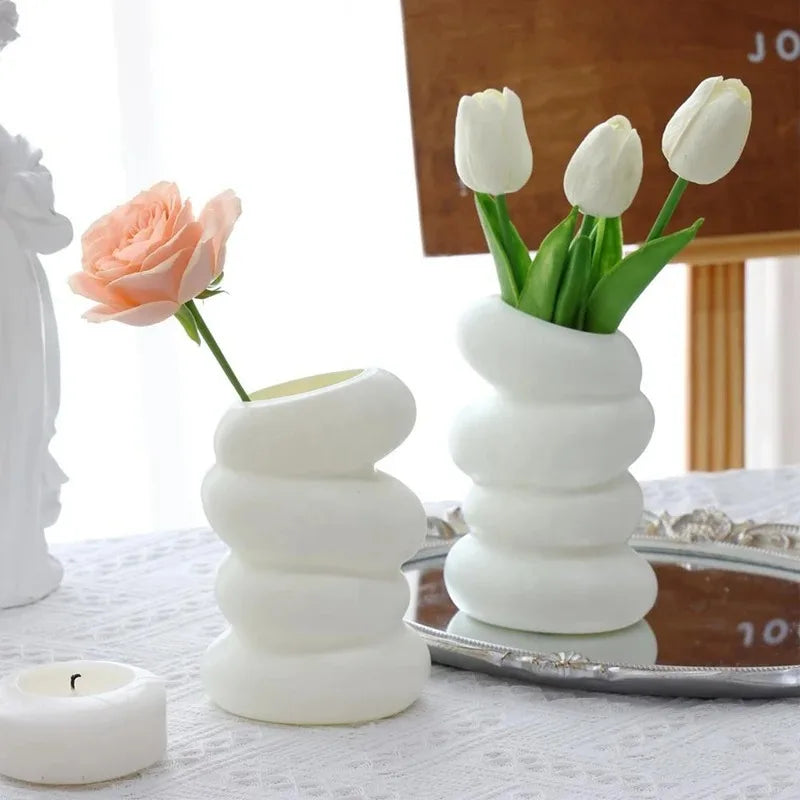 Plastic spiral white vase pair with stacked rounded segments; pink rose in one and white tulips in the other