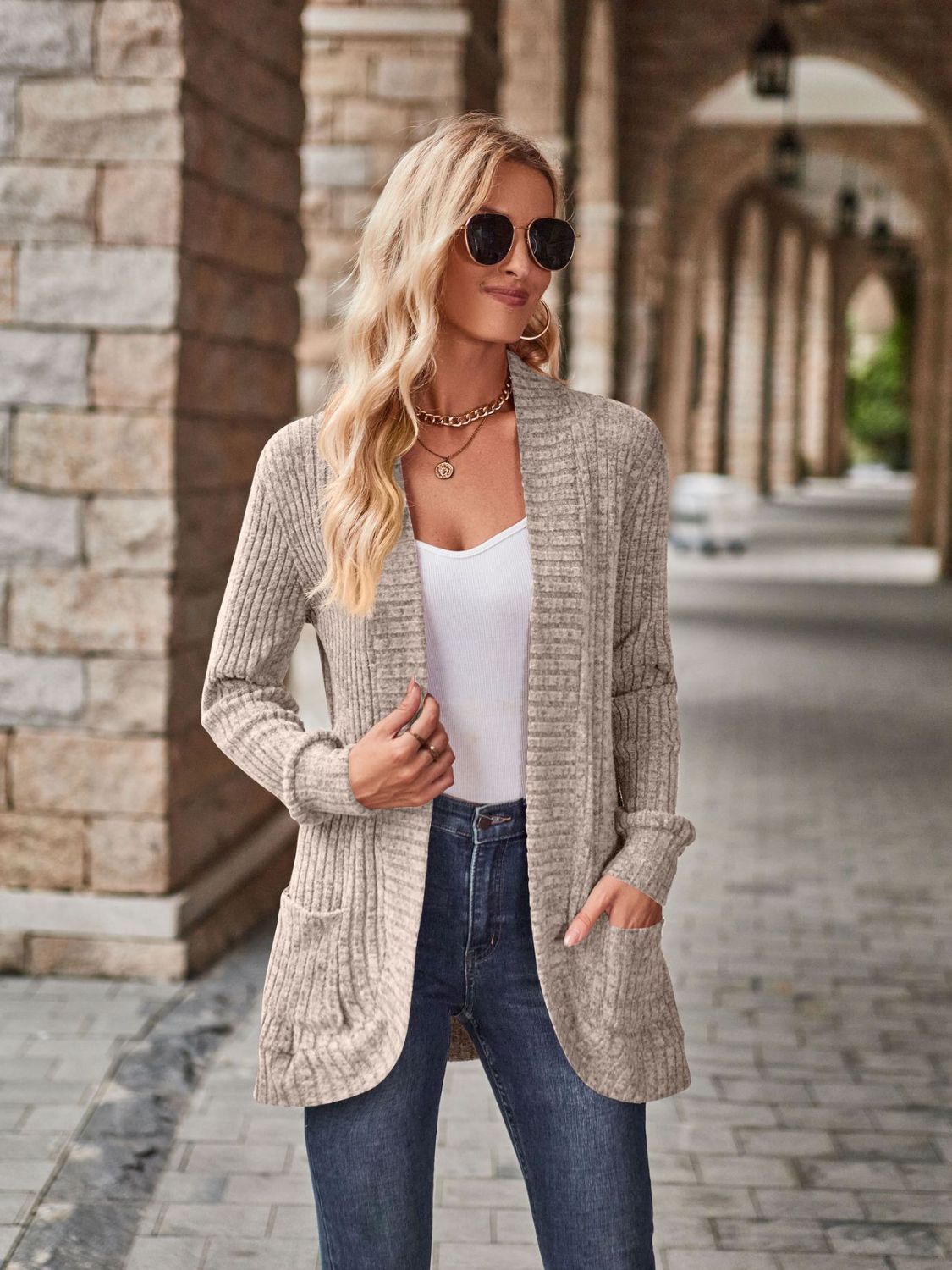 Stretchy open-front cardigan with deep side pockets in beige knit, worn by a woman in jeans.