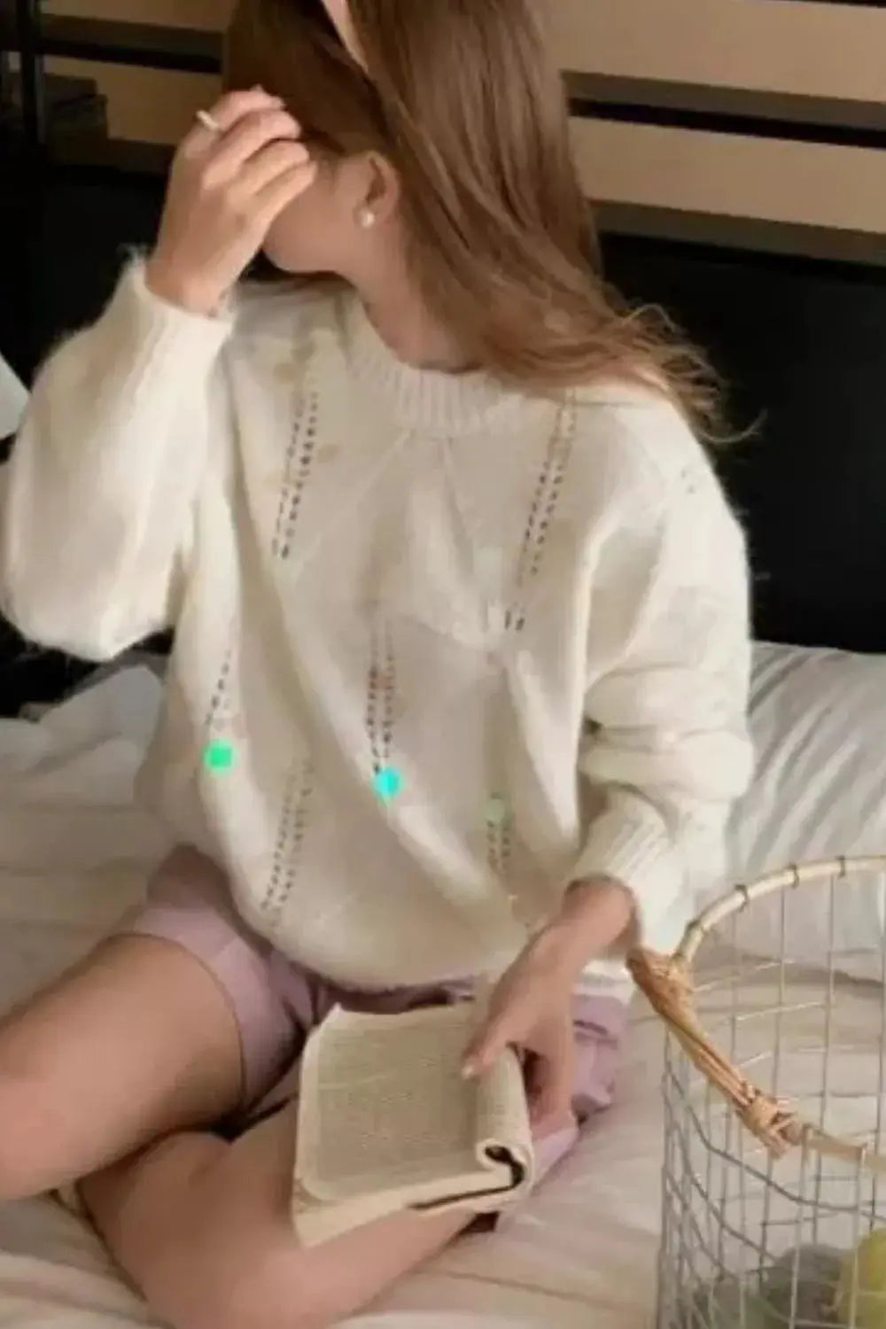 Shimmering sequin round-neck holiday sweater, white knit with vertical openwork panels on a seated woman