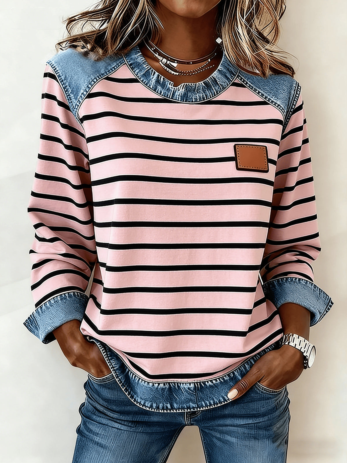 Women's patchwork denim sweatshirt in pink with black stripes, denim shoulder patches and rolled cuffs.