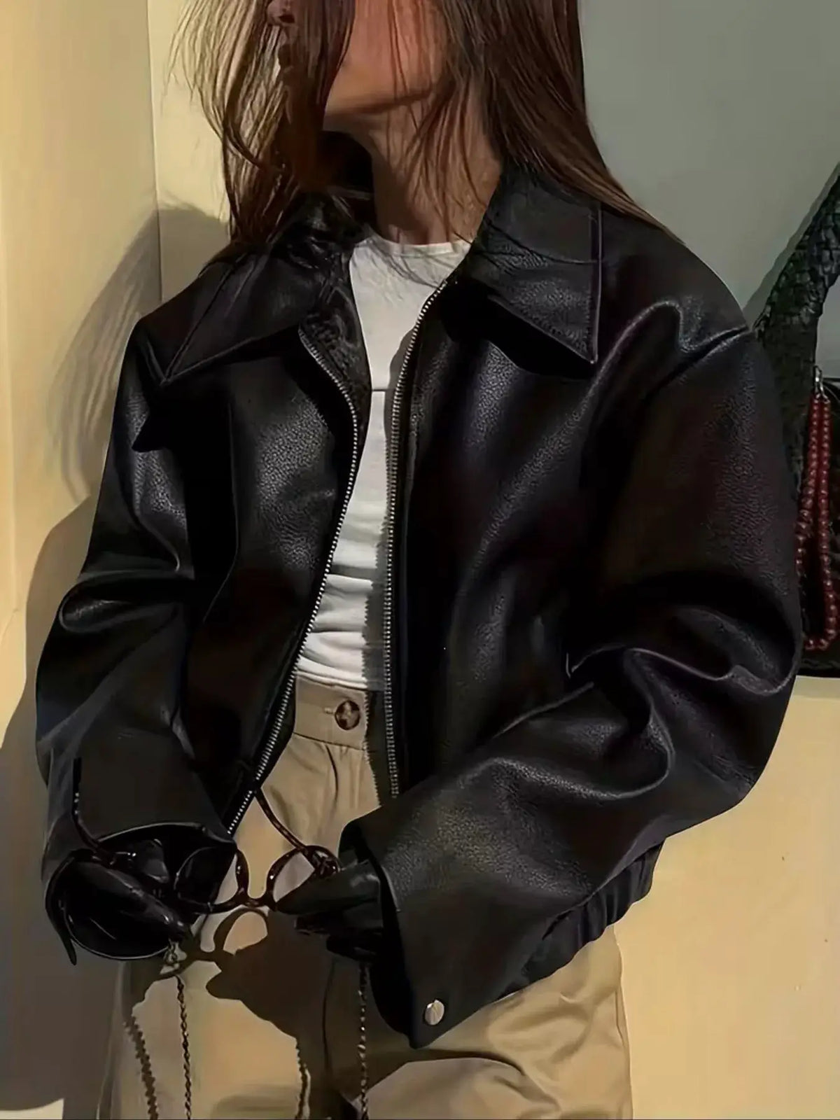 Oversized black faux leather moto jacket with a full zip front worn over a white tee