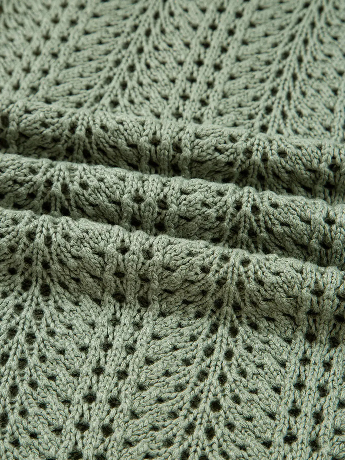 Lightweight scalloped-edge eyelet knit cardigan in sage green, showing textured stitches and soft yarn details