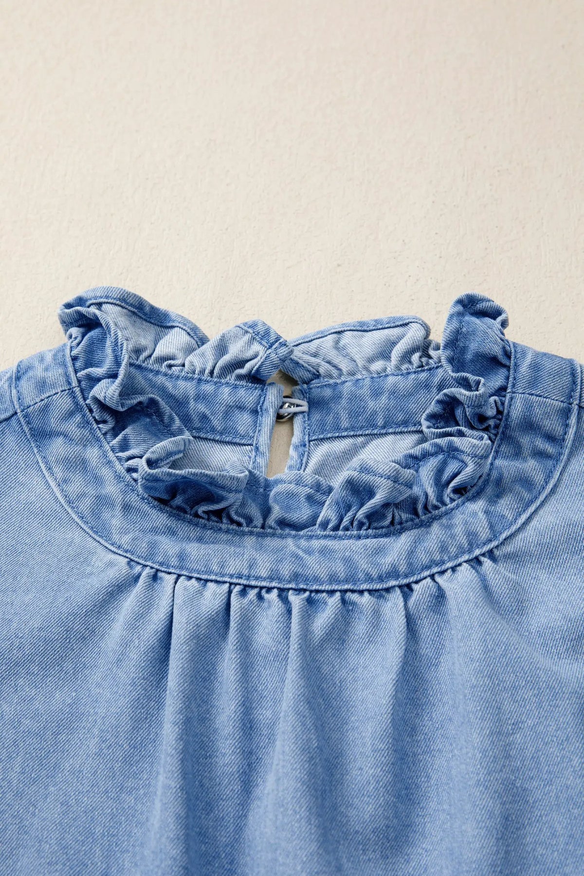 Distressed denim top with frill collar; light-blue wash