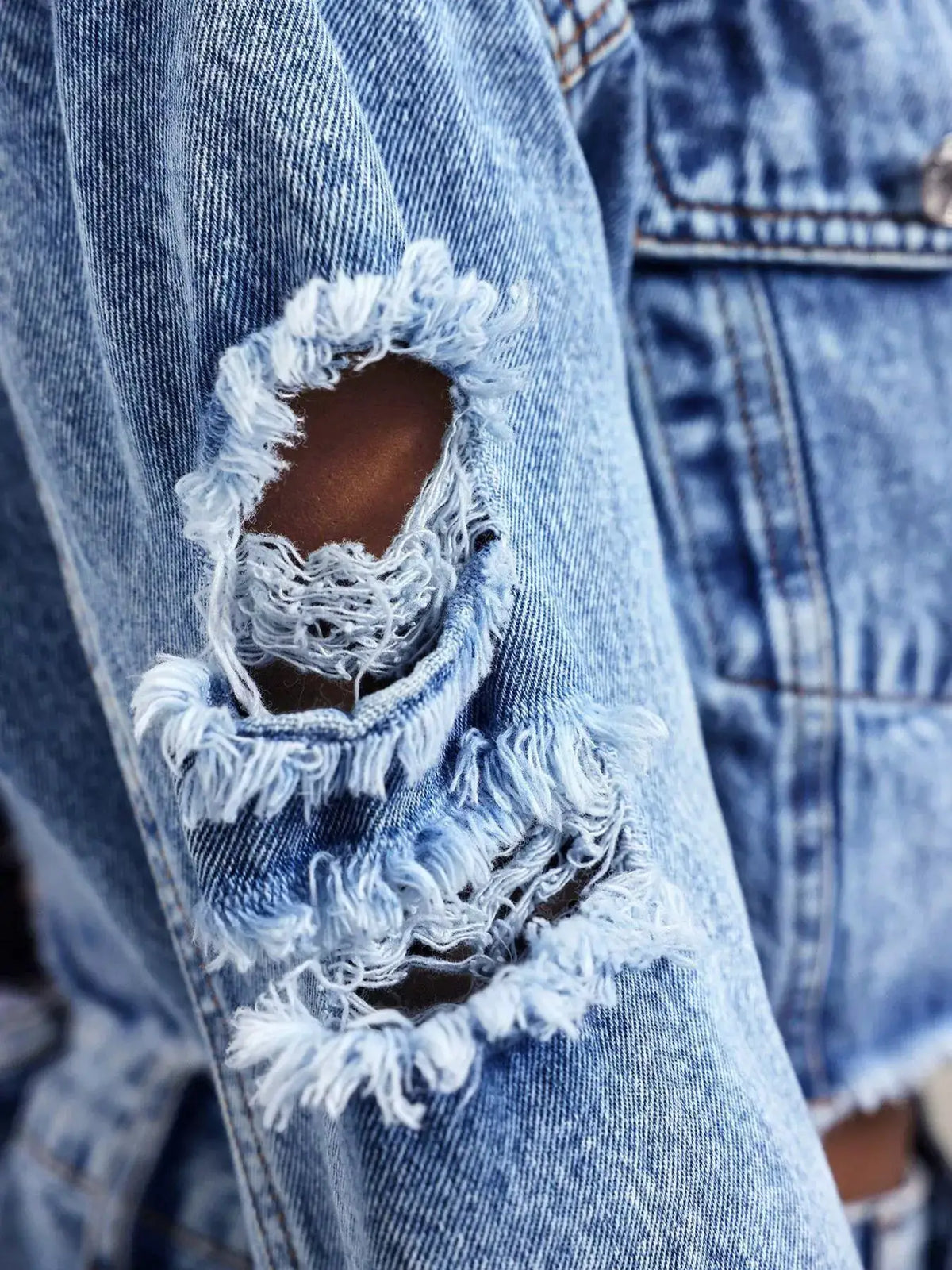 Distressed Ruffled Asymmetrical Cropped Denim Jacket in blue with frayed hole detail