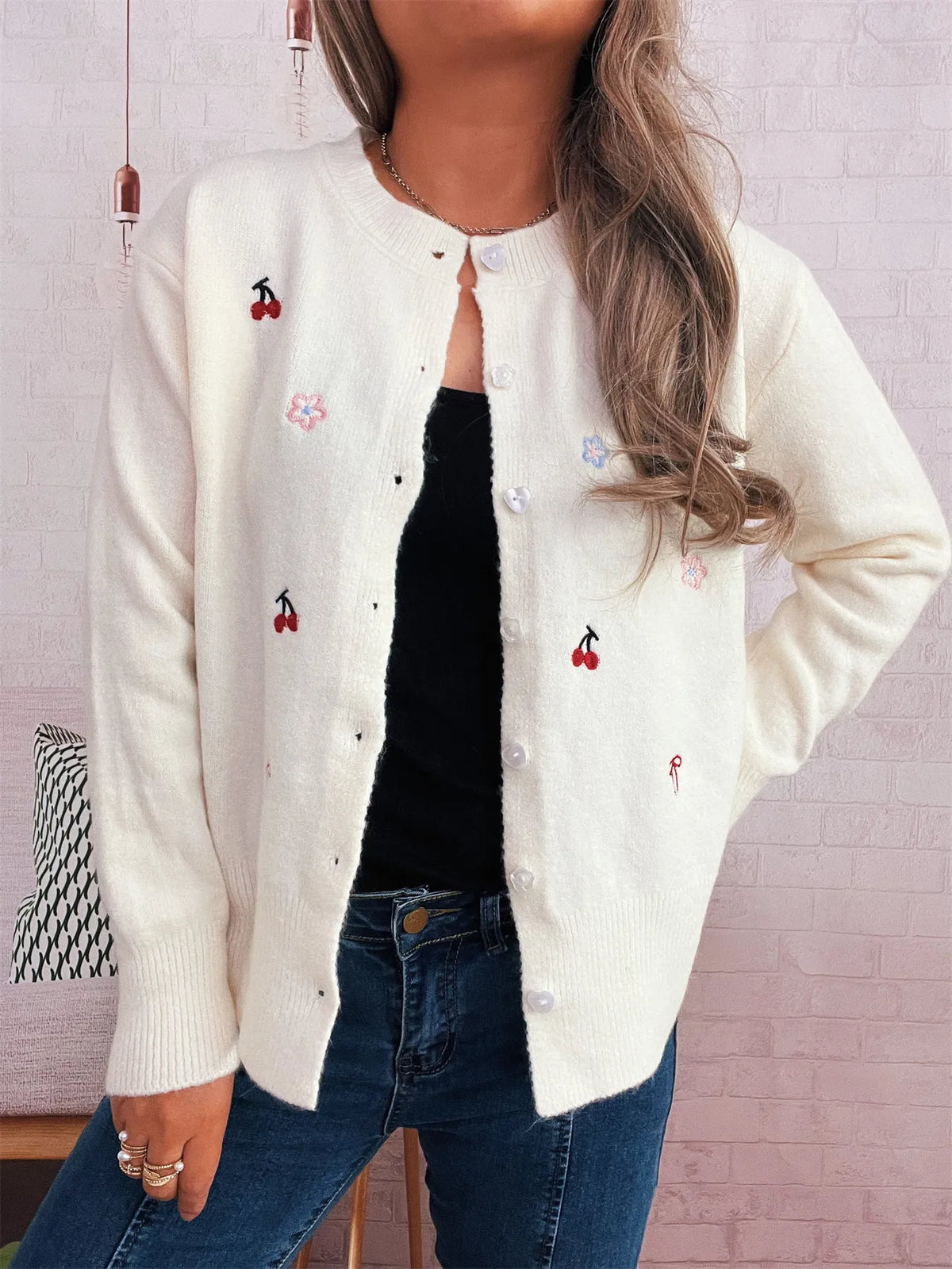 White ribbed button-front knit cardigan with cherry and floral embroidery.