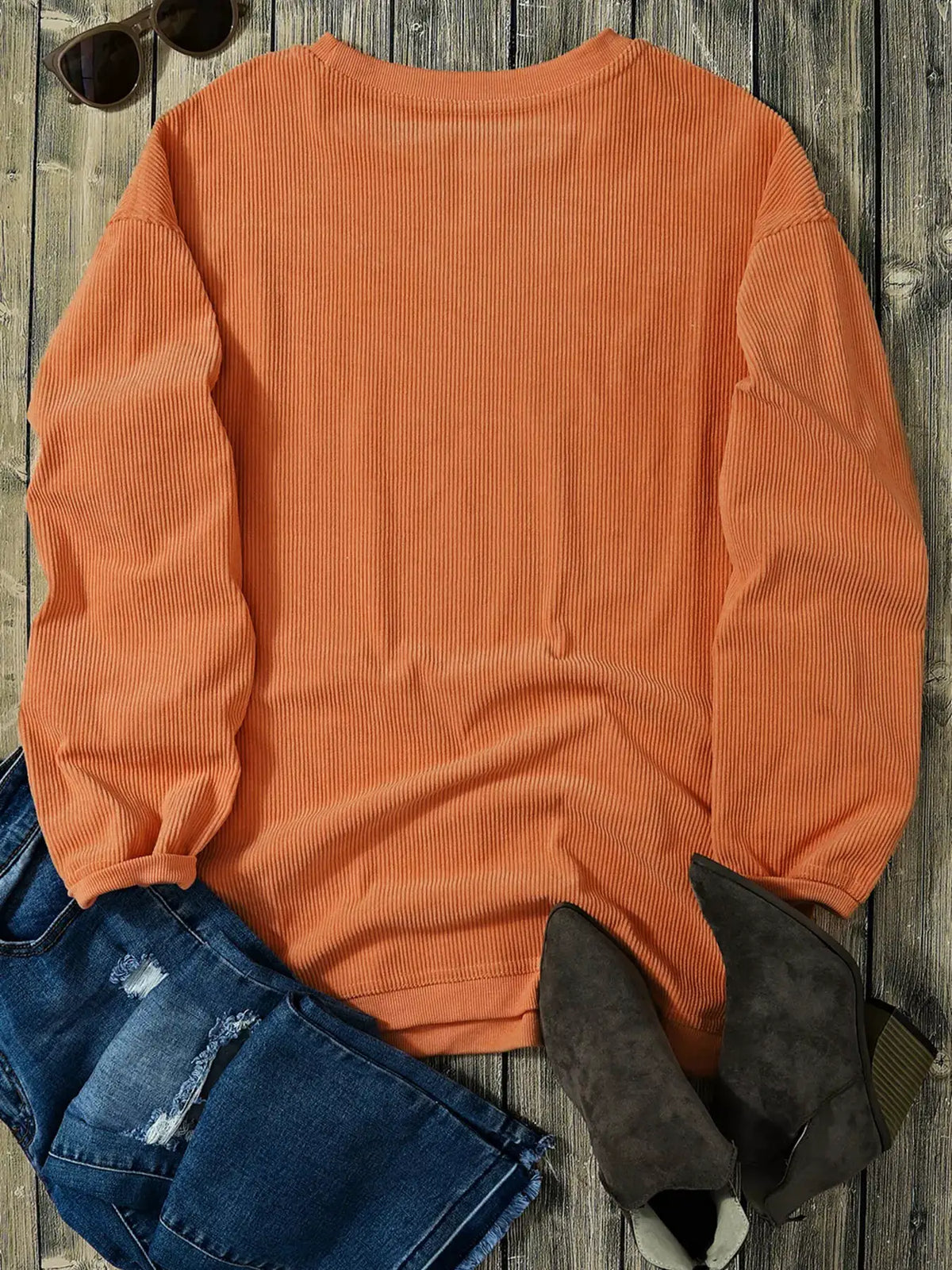 Orange ribbed knit sweatshirt displayed with jeans and boots for a casual fall look.