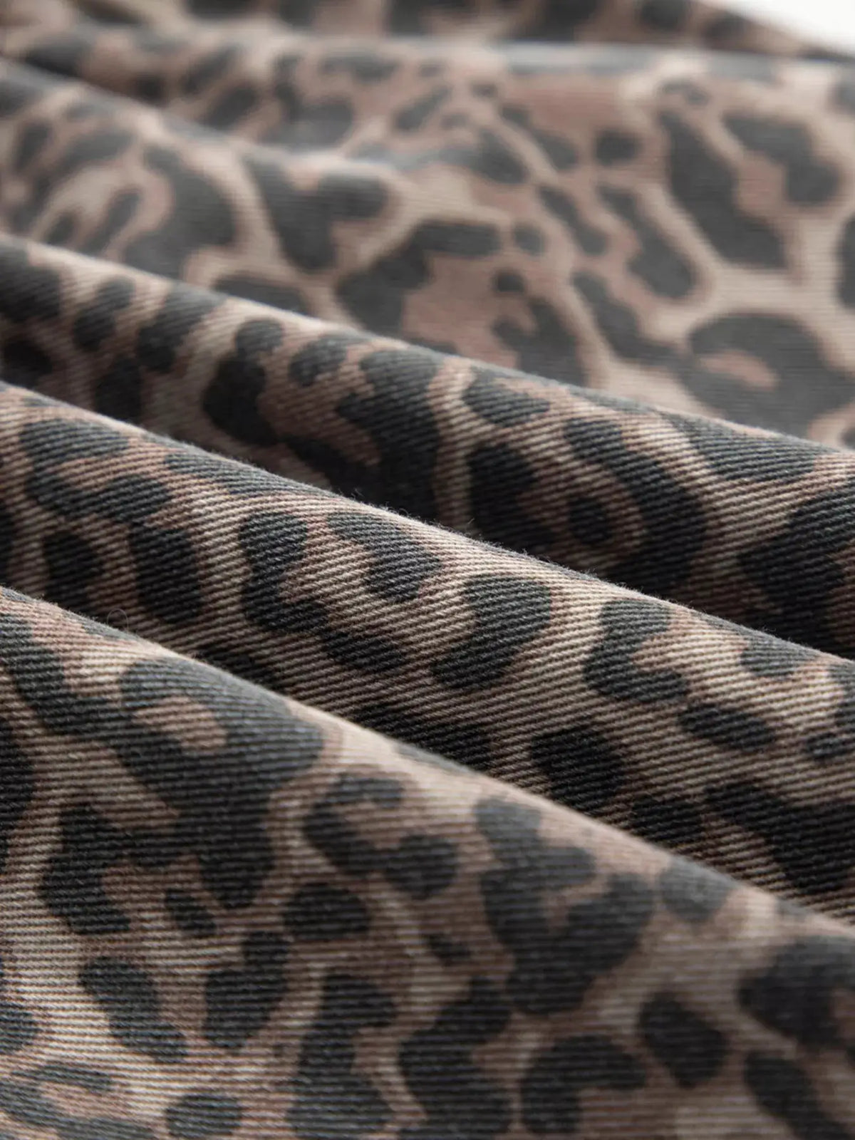 Women's leopard print denim top with a ruffle hem in tan and black.