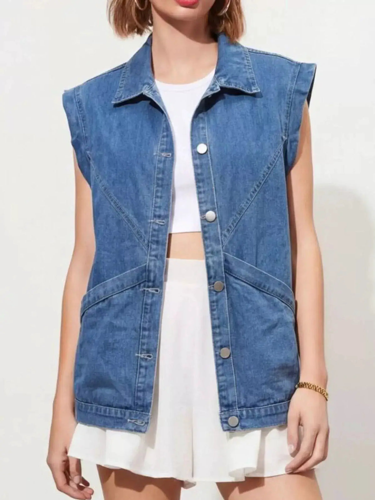 Faded button-down sleeveless denim vest with classic metal hardware, relaxed fit, worn over a white top.