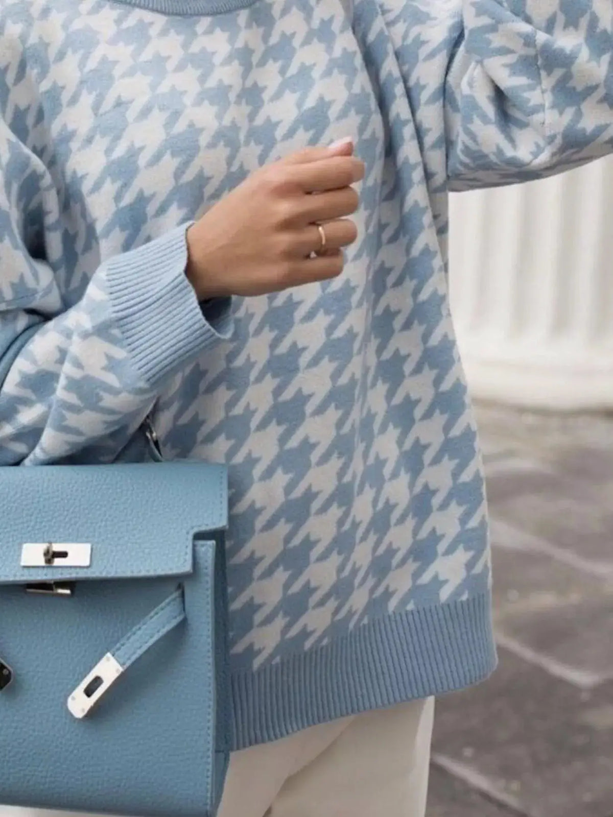 Classic oversized houndstooth sweater in blue and white with ribbed cuffs, paired with a blue handbag