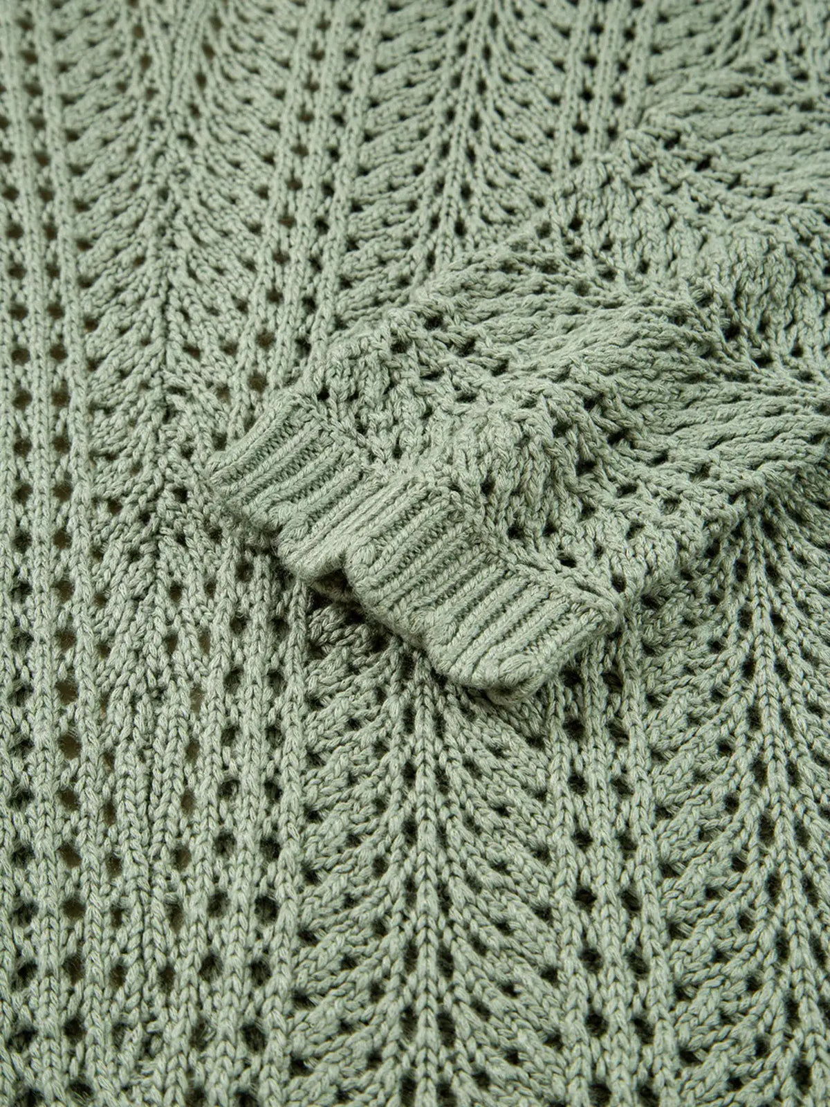 Cardigan fabric close-up: sage green eyelet knit with scalloped edges.