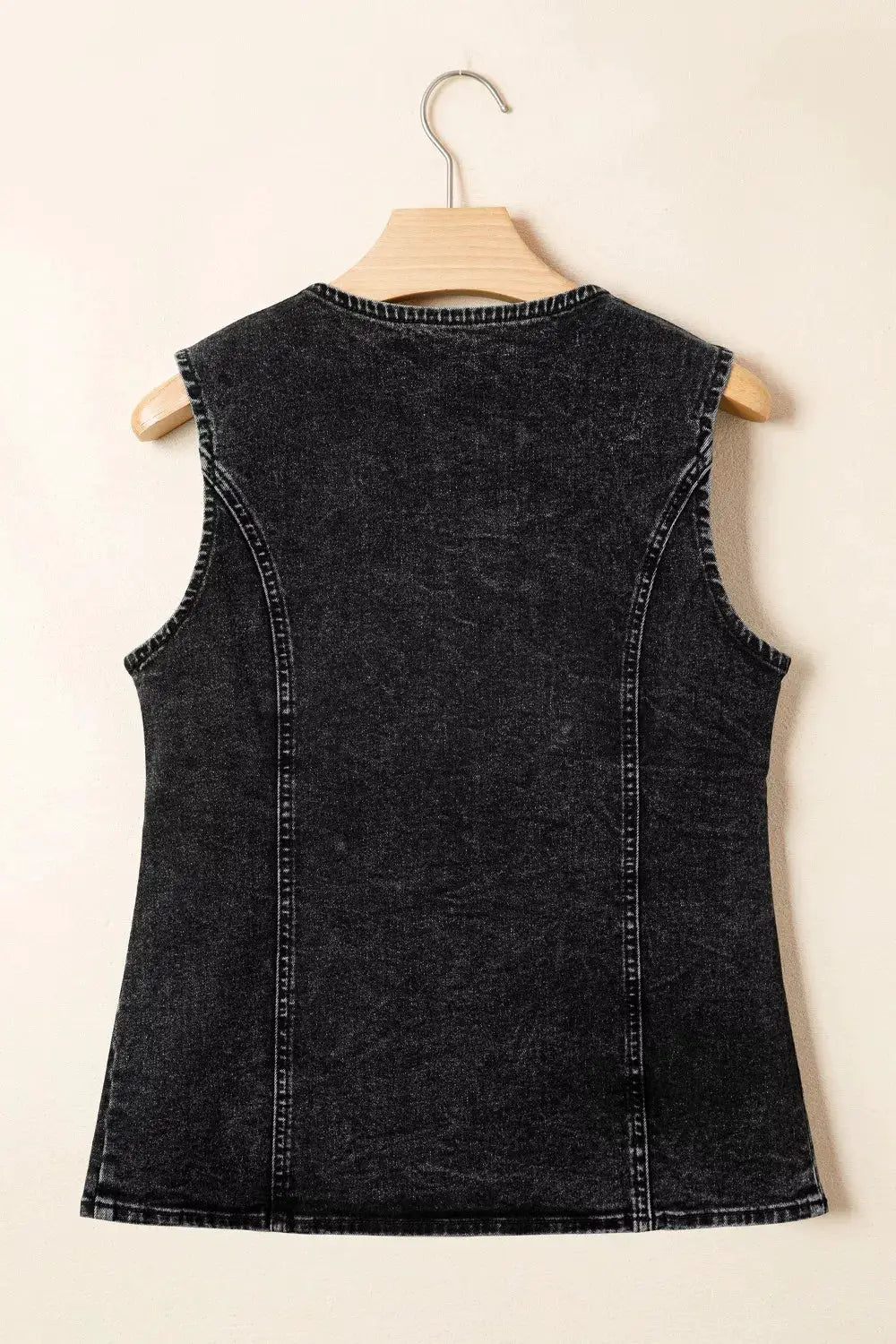 Vintage wash black denim vest, sleeveless with back seams on a wooden hanger