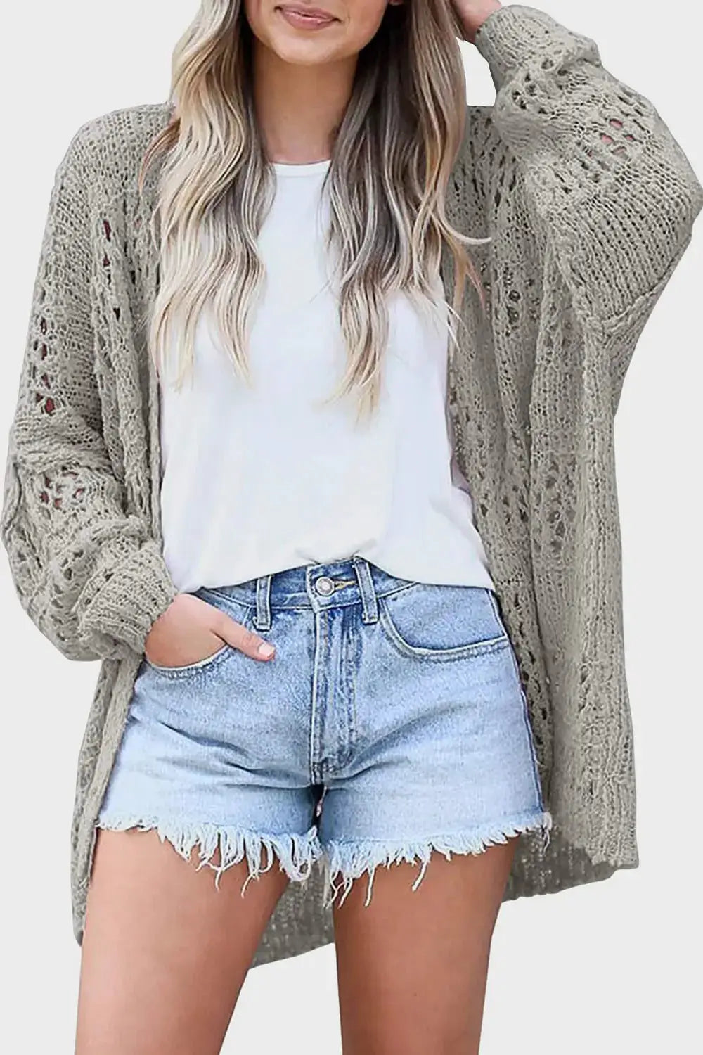 Openwork open-front cardigan in taupe acrylic with long sleeves, worn over a white top and light denim shorts.