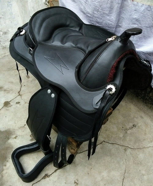 Black synthetic treeless Western saddle with stirrups and silver hardware.