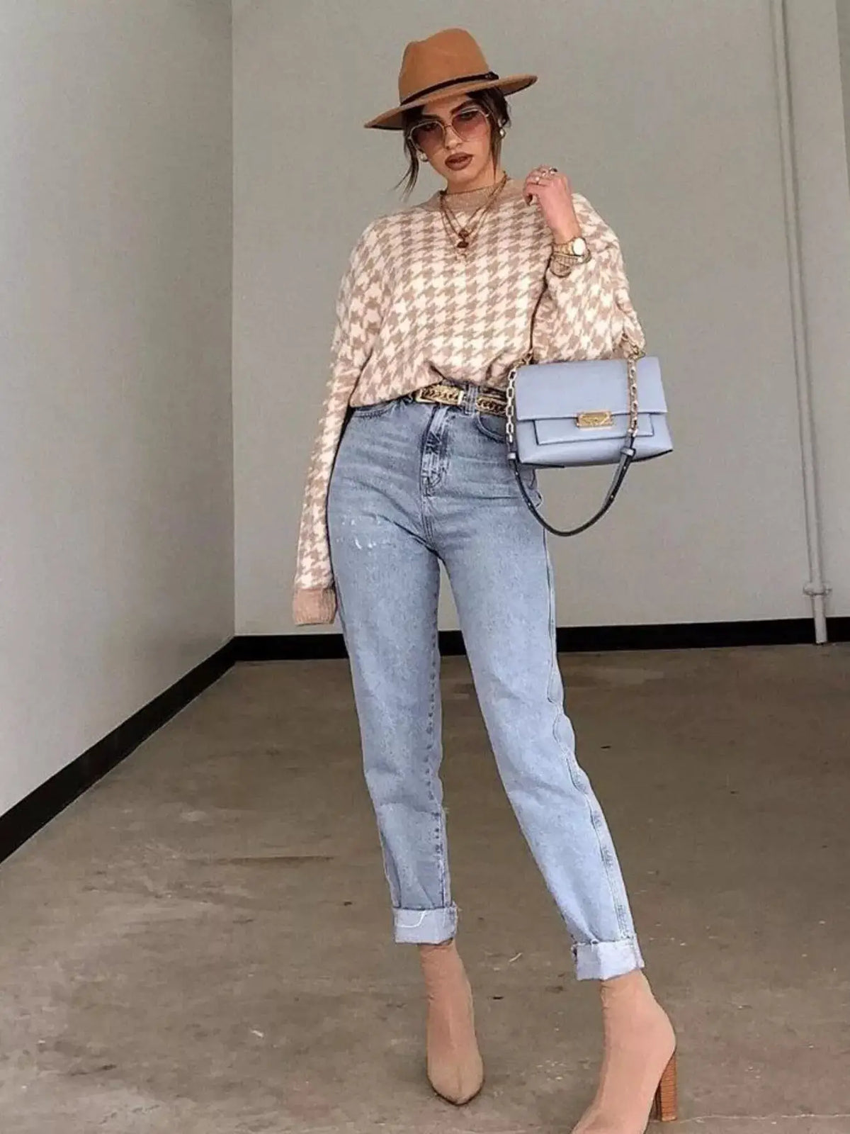 Classic oversized houndstooth sweater in beige, paired with light-wash jeans and a lavender handbag with gold hardware.