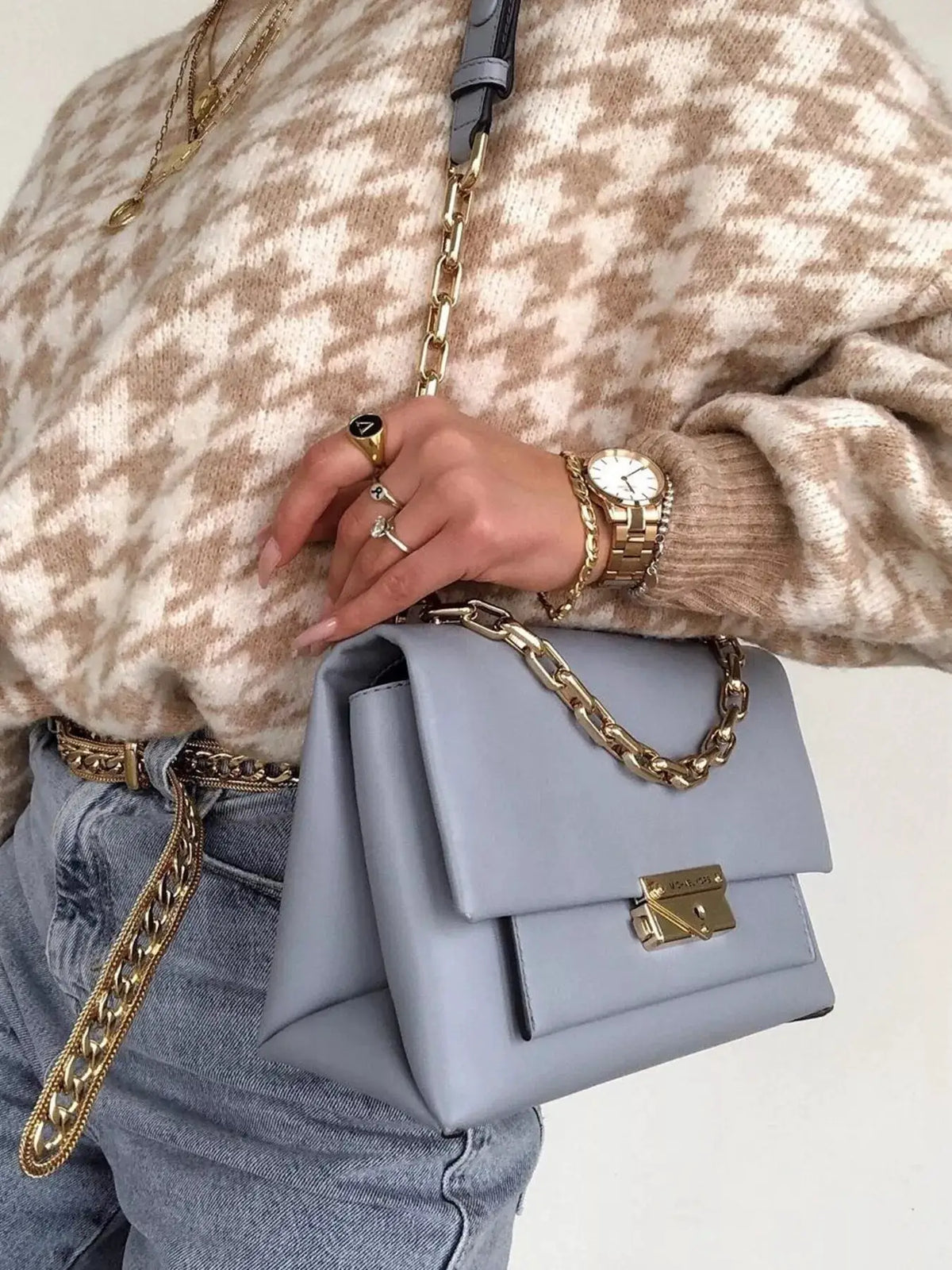 Classic oversized houndstooth sweater in beige and cream; paired with a light blue handbag and gold jewelry