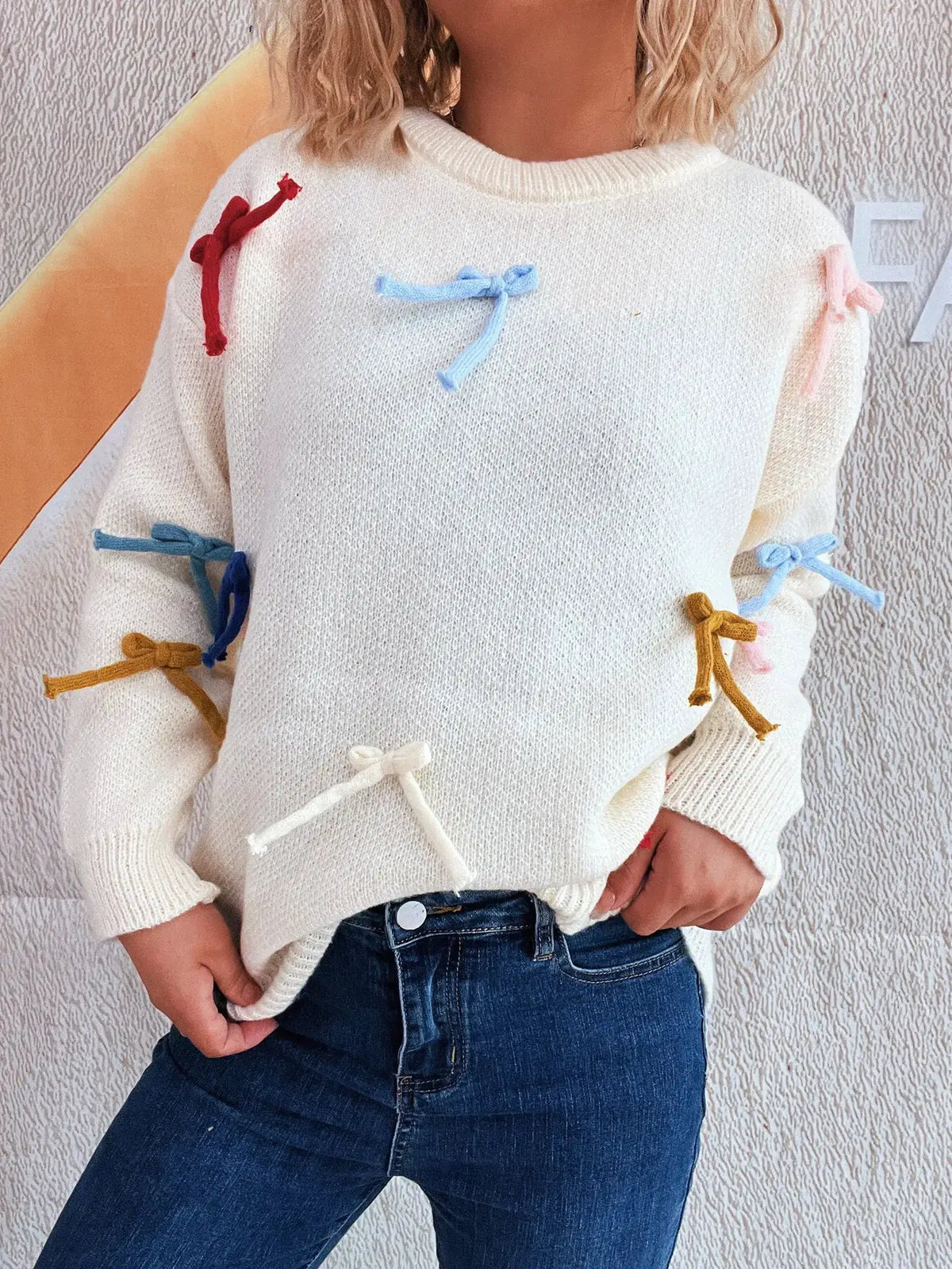 Vibrant Bow Accent Round Neck Sweater white knit pullover with colorful bows on sleeves.