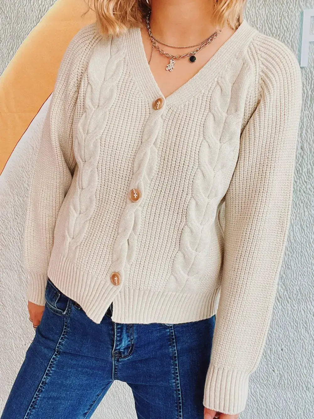 Soft cable knit V-neck cardigan in cream with wooden button-front detail.