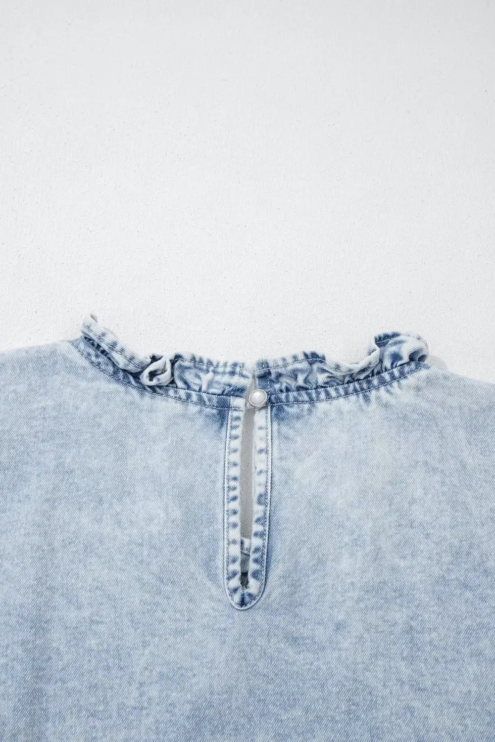 Vintage washed denim top in light blue with delicate ruffle neckline and back button closure.