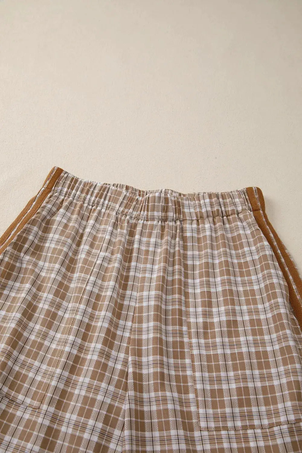 Plaid print casual pants with elastic waistband and tie detail in tan and white.