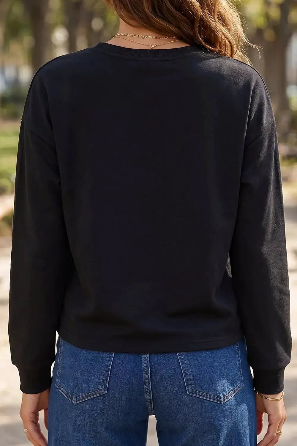 Rhinestone Pumpkin Long Sleeve Sweatshirt, black; back view of model in jeans outdoors