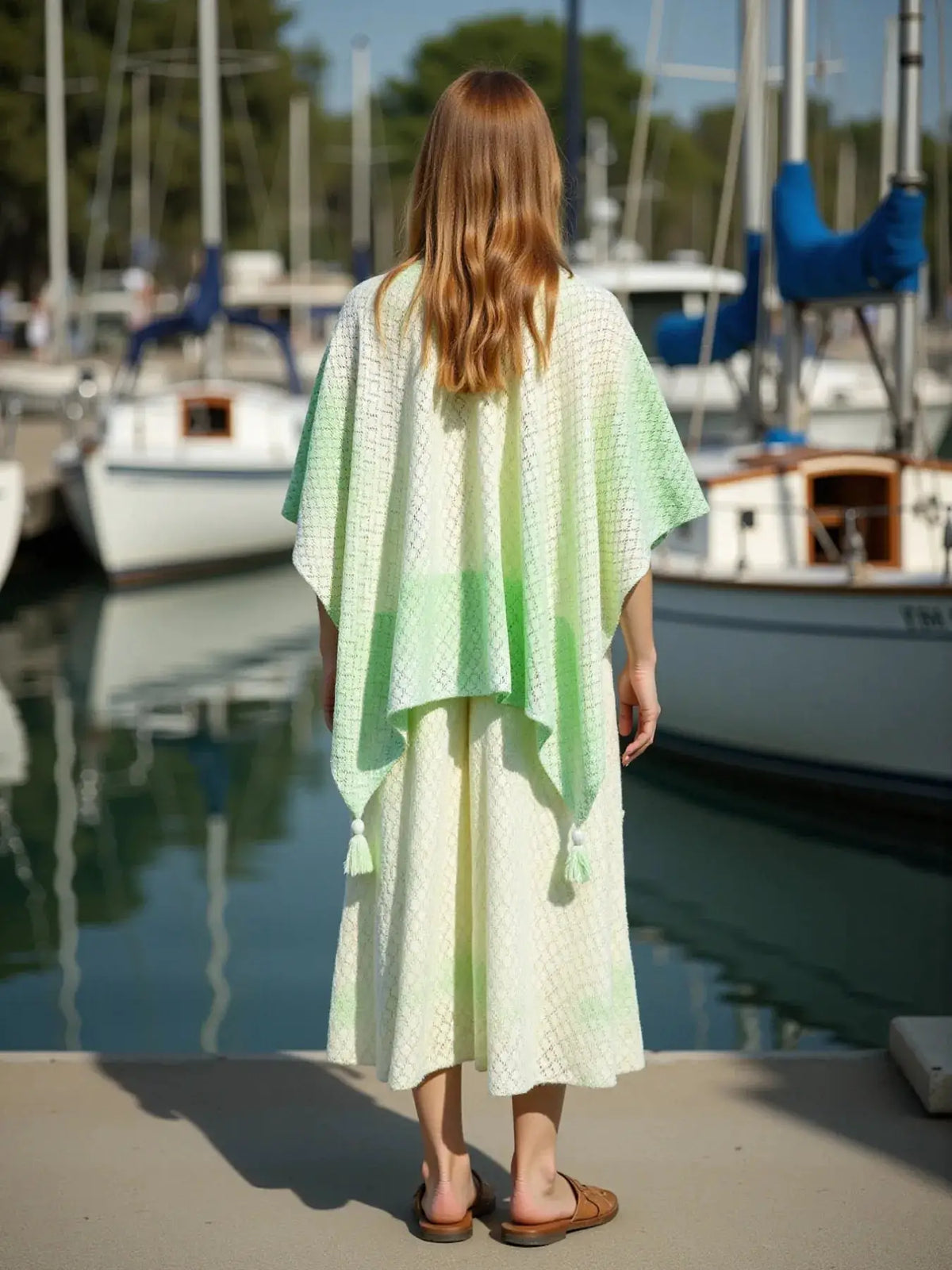 Lightweight gradient openwork knit tassel beach cover-up in pastel yellow and green; back view on model at the marina