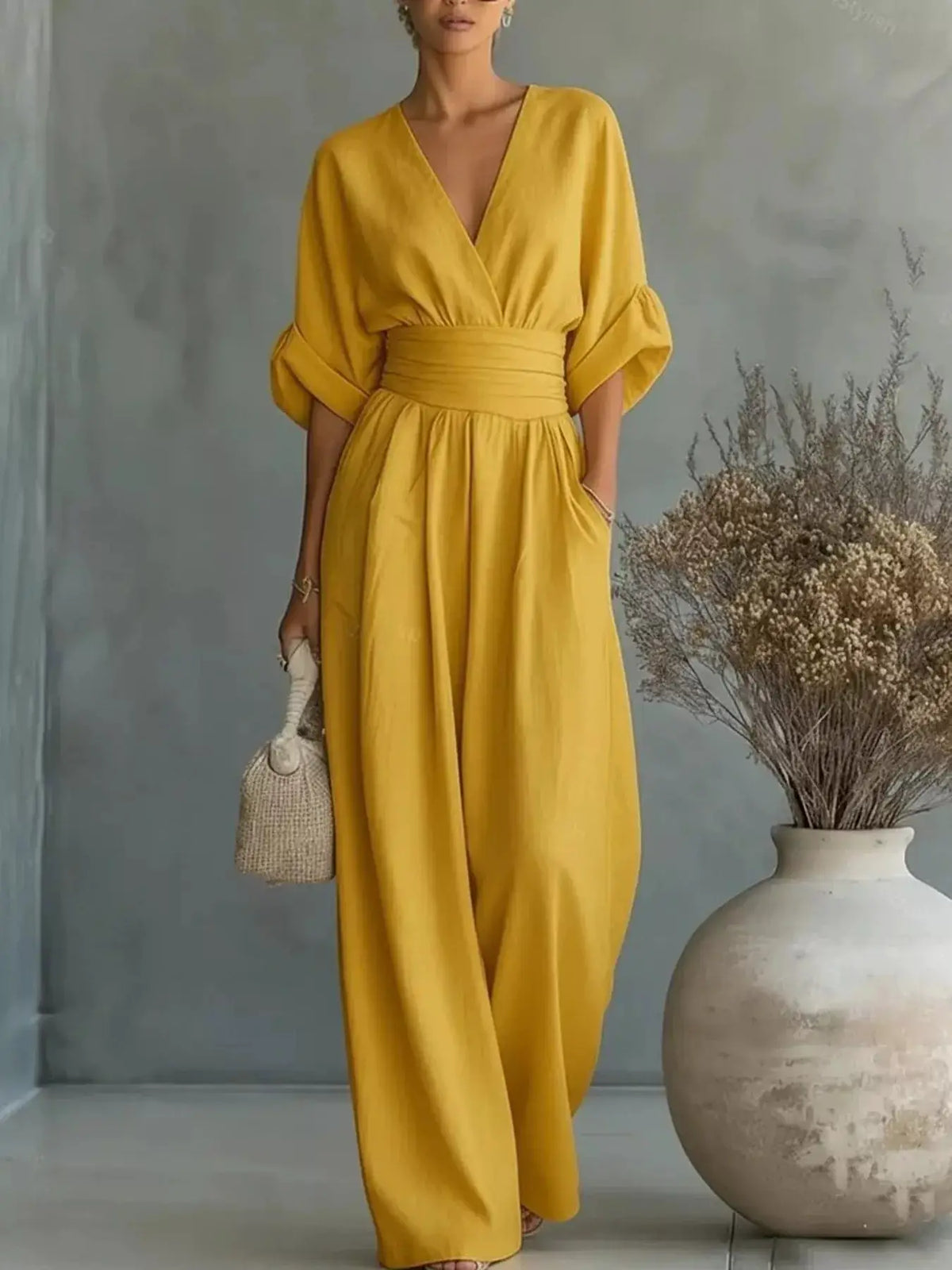 Plus-size mustard yellow wrap-front jumpsuit with V-neck, puff half sleeves, cinched waist, and wide-leg pants.