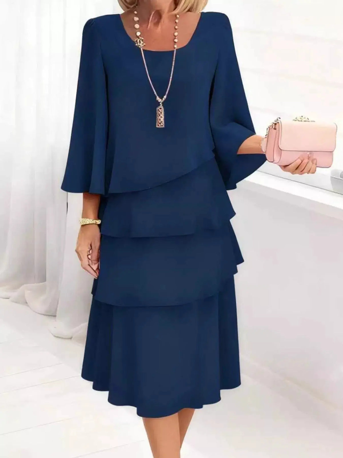 Plus-size navy blue ruffled layered dress with 3/4 sleeves; pink clutch shown