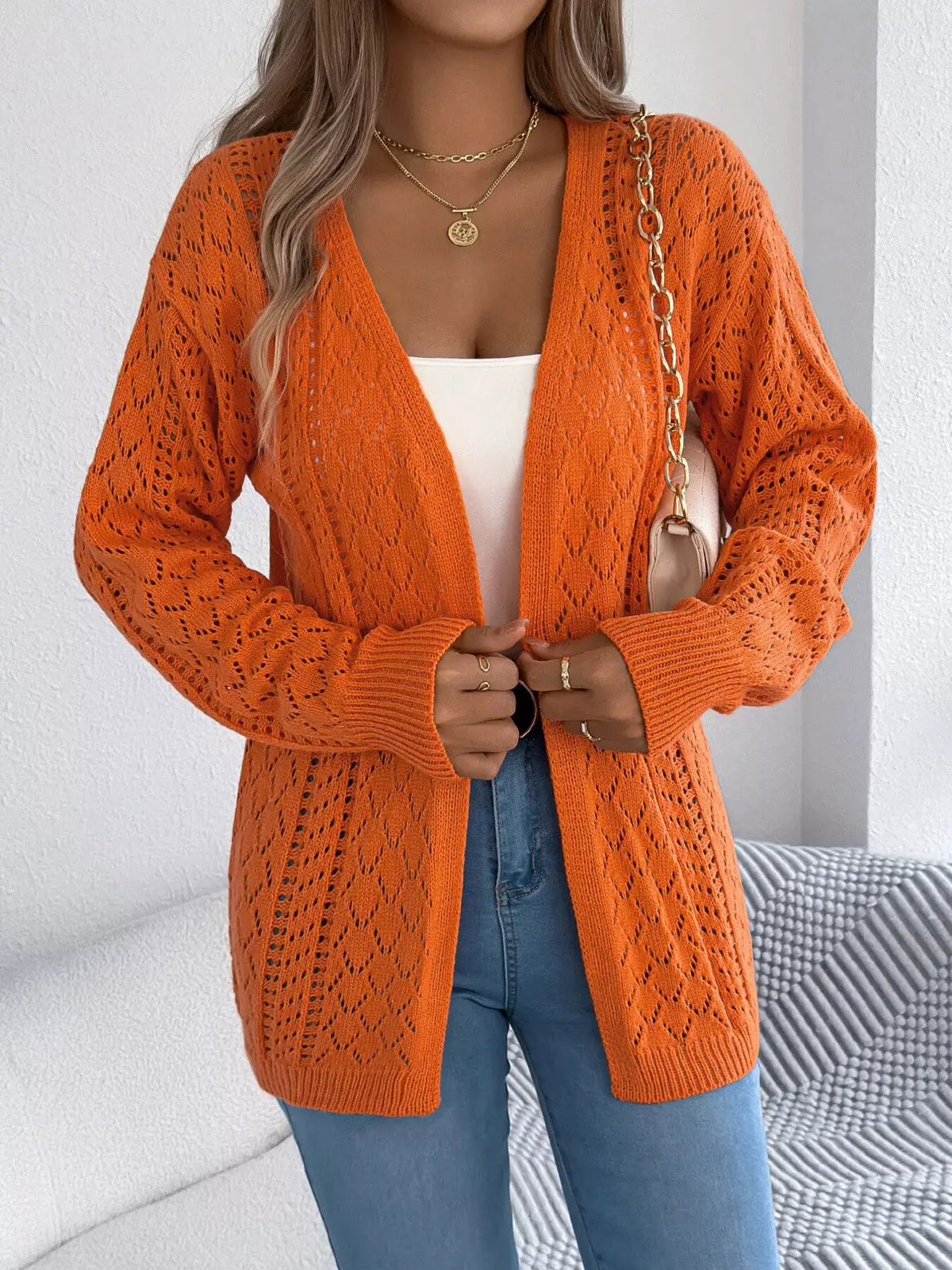 Openwork long-sleeve cardigan for women in orange, open-front knit worn over white top with blue jeans