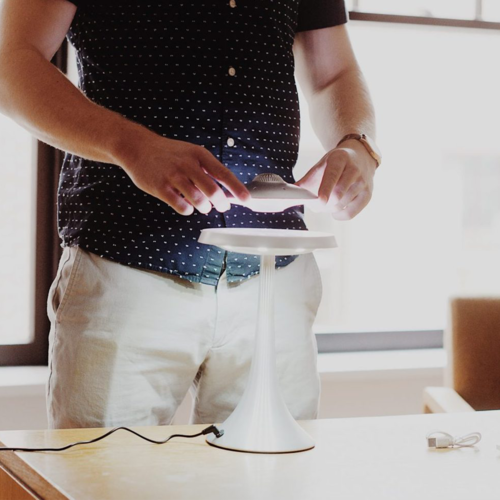 Levitating UFO speaker, white plastic, on a white pedestal desk setup.