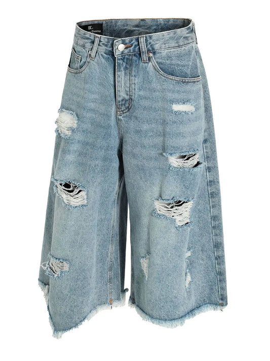 Mens oversized distressed denim shorts in light wash blue cotton blend with frayed hems and multiple rips.